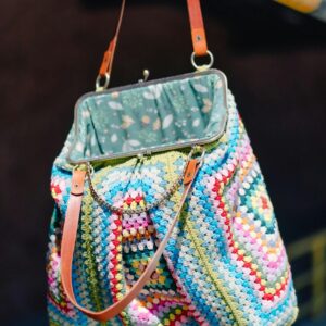 Foto de straupelechit Vibrant multicolored crochet handbag with leather straps hanging on a bar.